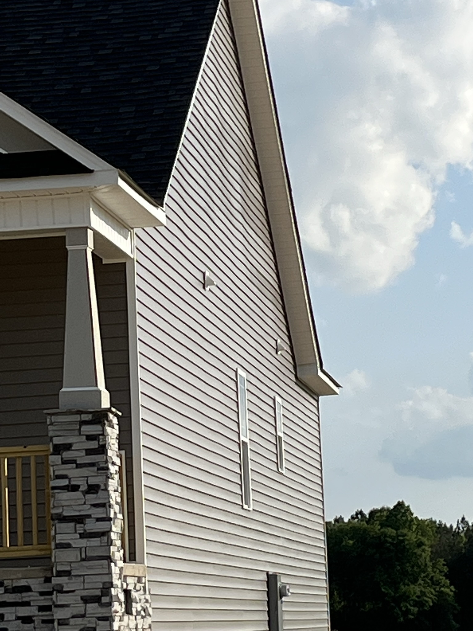 Wavy vinyl siding on a second-story gable wall caused by a combination of bowed sheathing and framing