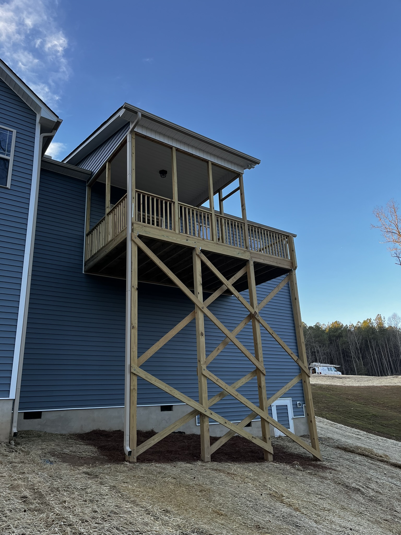 Tall framed crawlspace wall with temporary diagonal bracing on a sloped lot