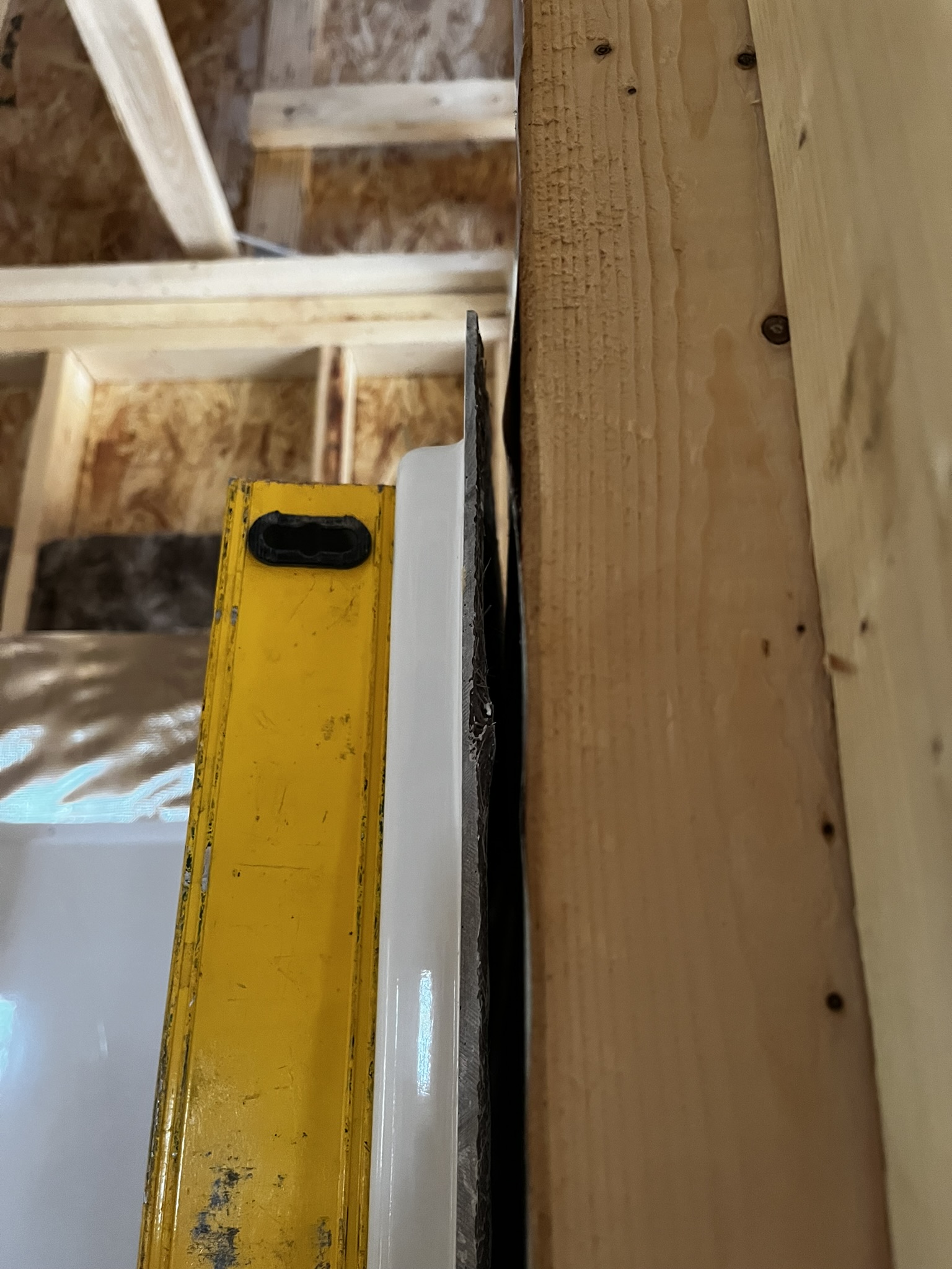 Fiberglass shower unit revealing a gap against an out-of-plumb wall stud during rough-in
