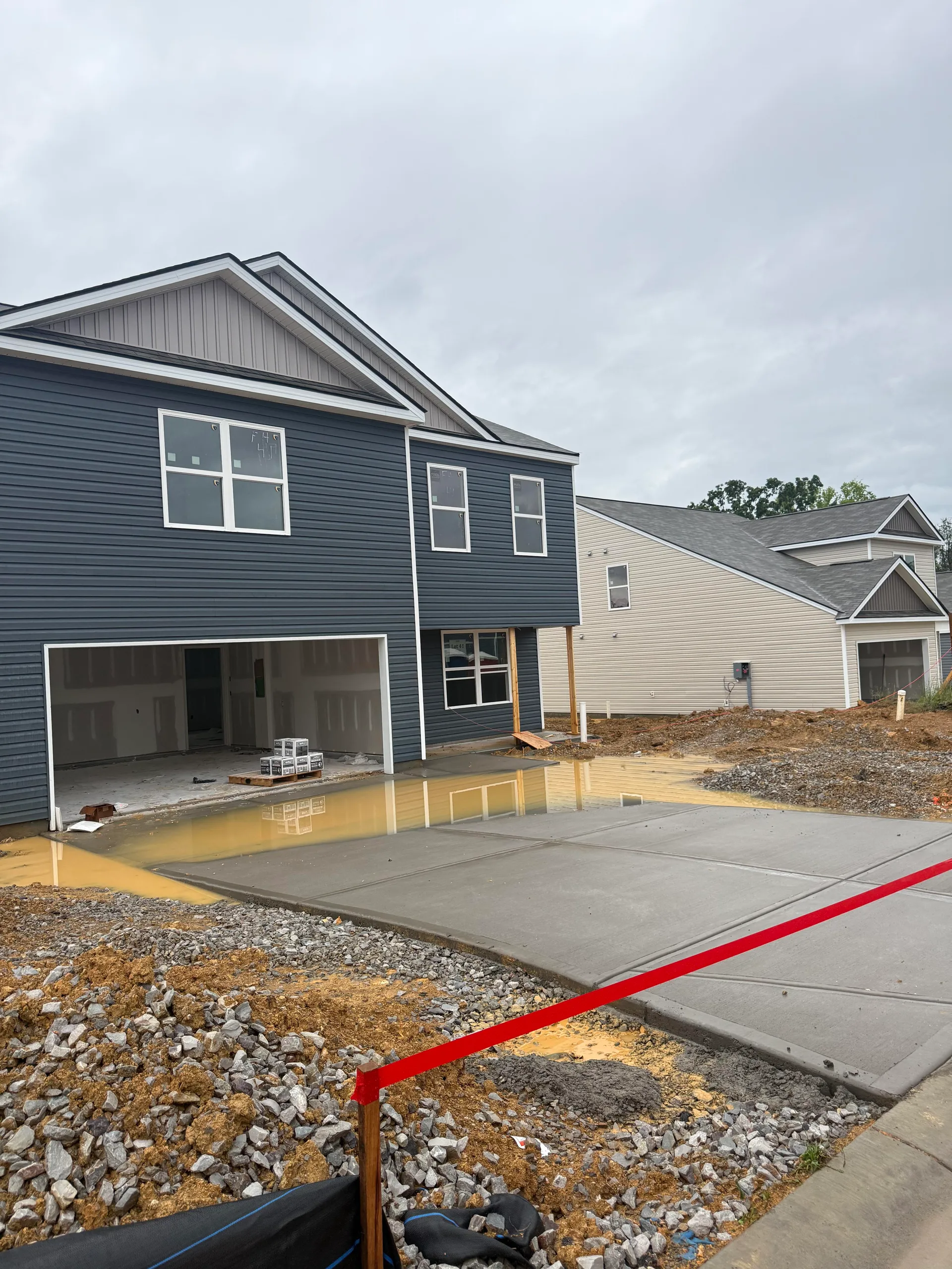 Driveway flooding on new construction home due to improper lot grading and insufficient fall away from foundation